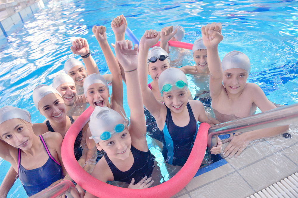 group of happy kids children at swimming pool class learning to swim